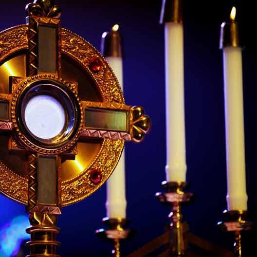 A monstrance holding the Blessed Sacrament, and candles